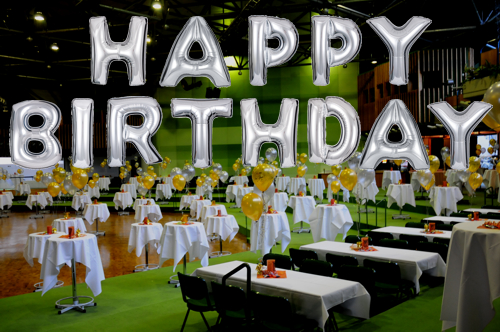 Happy-Birthday-mit-grossen-silbernen-Buchstaben-Luftballons
