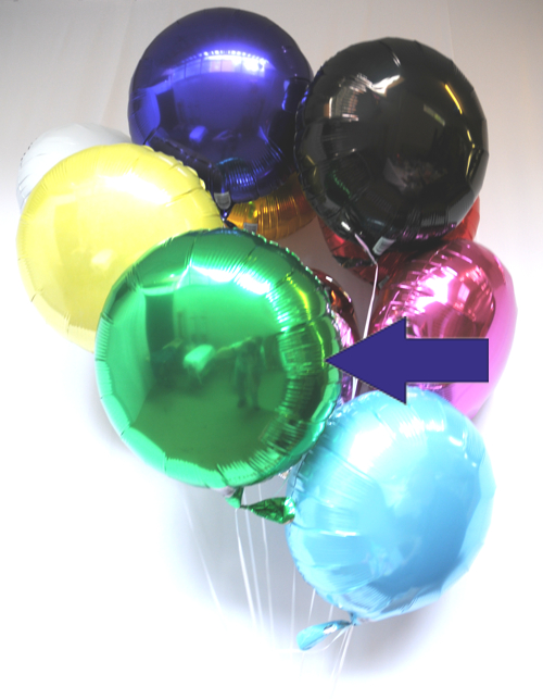 Traube mit runden Luftballons aus Folie. Pfeil: Rundballon in Grün